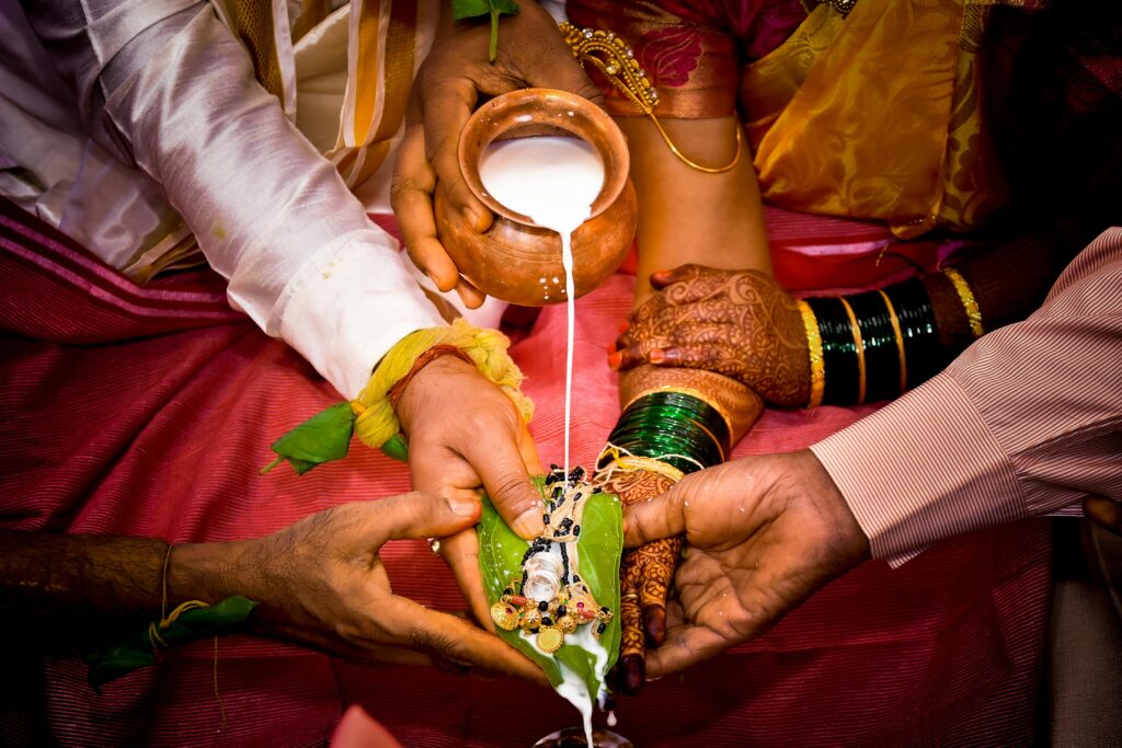 Close-up of a traditional Indian wedding ritual involving milk pouring on hands, depicting cultural values and symbolism.