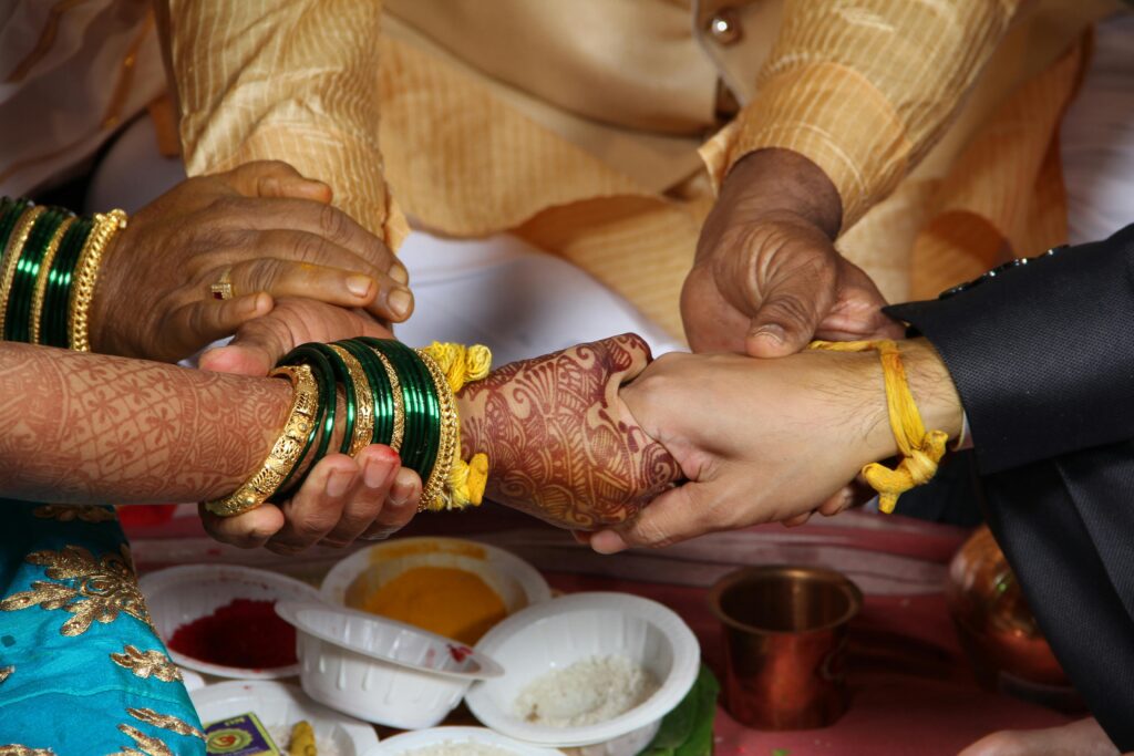 An intimate moment captured during a Hindu wedding ritual, showcasing henna-adorned hands.